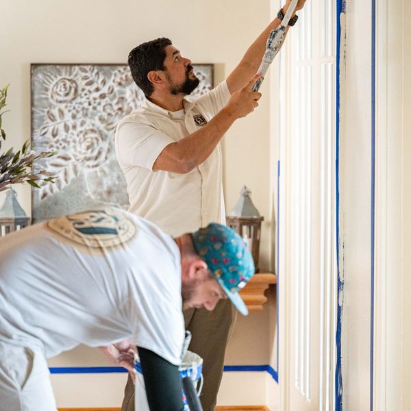 Benefits of Working With Residential Painting Contractors3 Painters tape off a window frame for residential painting.