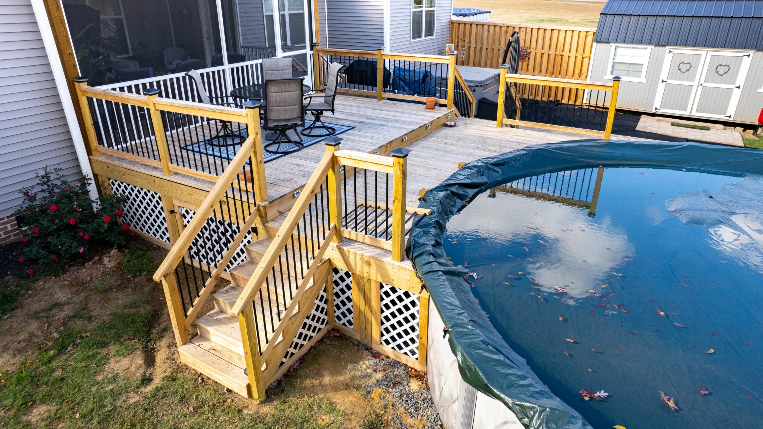 Wooden deck with stairs next to an above-ground pool, before renovation.