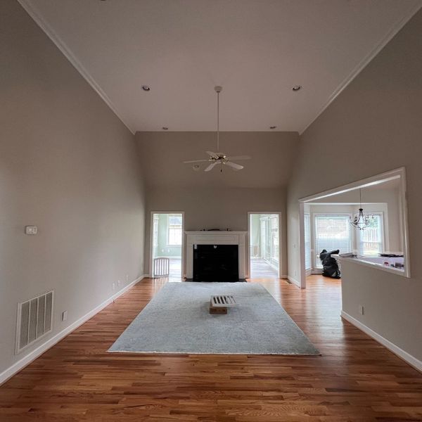 How Much Does it Cost to Paint a Living Room Empty living room with fireplace, vaulted ceiling, and light blue rug