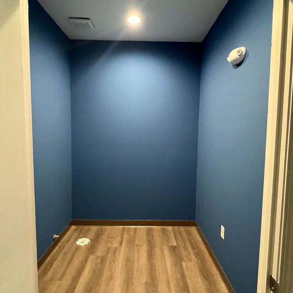 HowCanIKeepPaintFromDryingOut-1 Empty small room with blue walls and wood-look flooring, possibly a storage closet.
