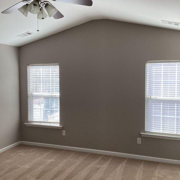Install New Carpet Before or After Painting_-image3 Empty room with beige carpet, neutral walls, and two windows.