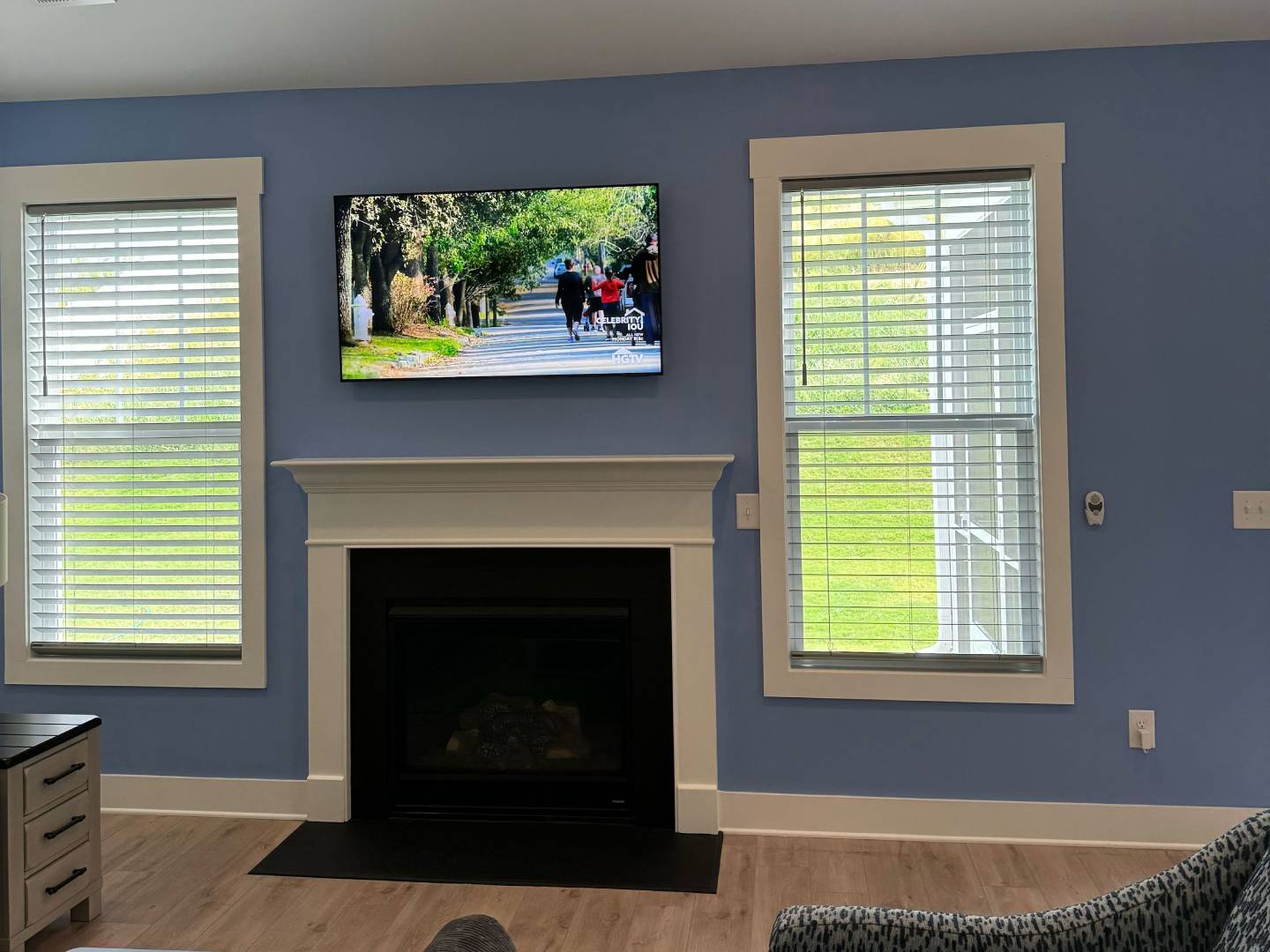 Blue living room with fireplace, TV, and large windows