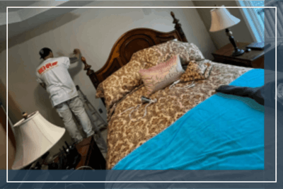 Painter in white suit painting bedroom wall, interior pricing focus.
