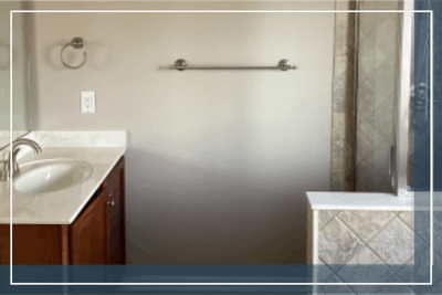 Modern bathroom vanity with marble countertop, shower stall, and towel bar.