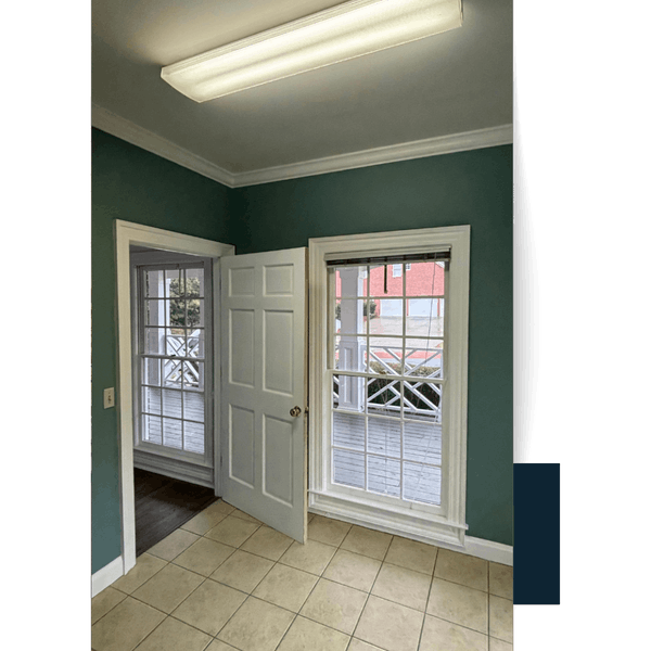 Portfolio Interior view of a room with teal walls, white trim, and two windows looking out to a porch.