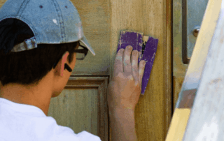 Portfolio 291 Person sanding a wooden door for refinishing.