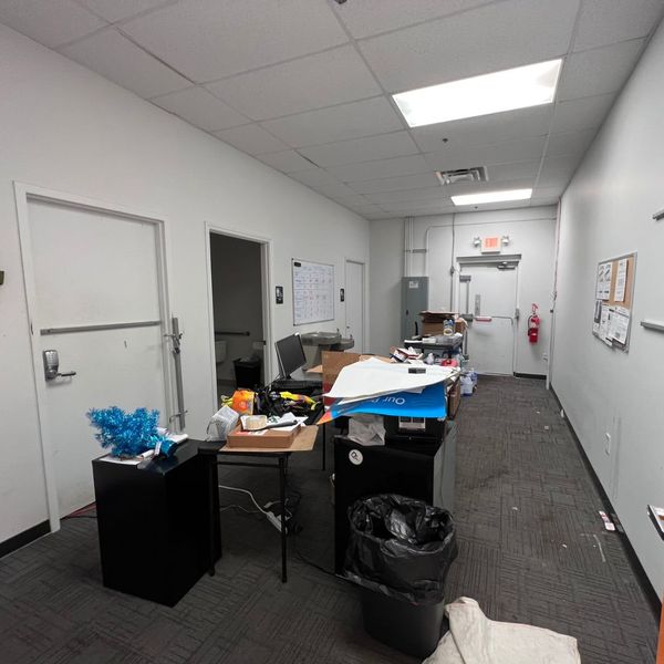 PrepYourOffice 29 Messy office hallway with desks, doors, and trash before commercial painting.