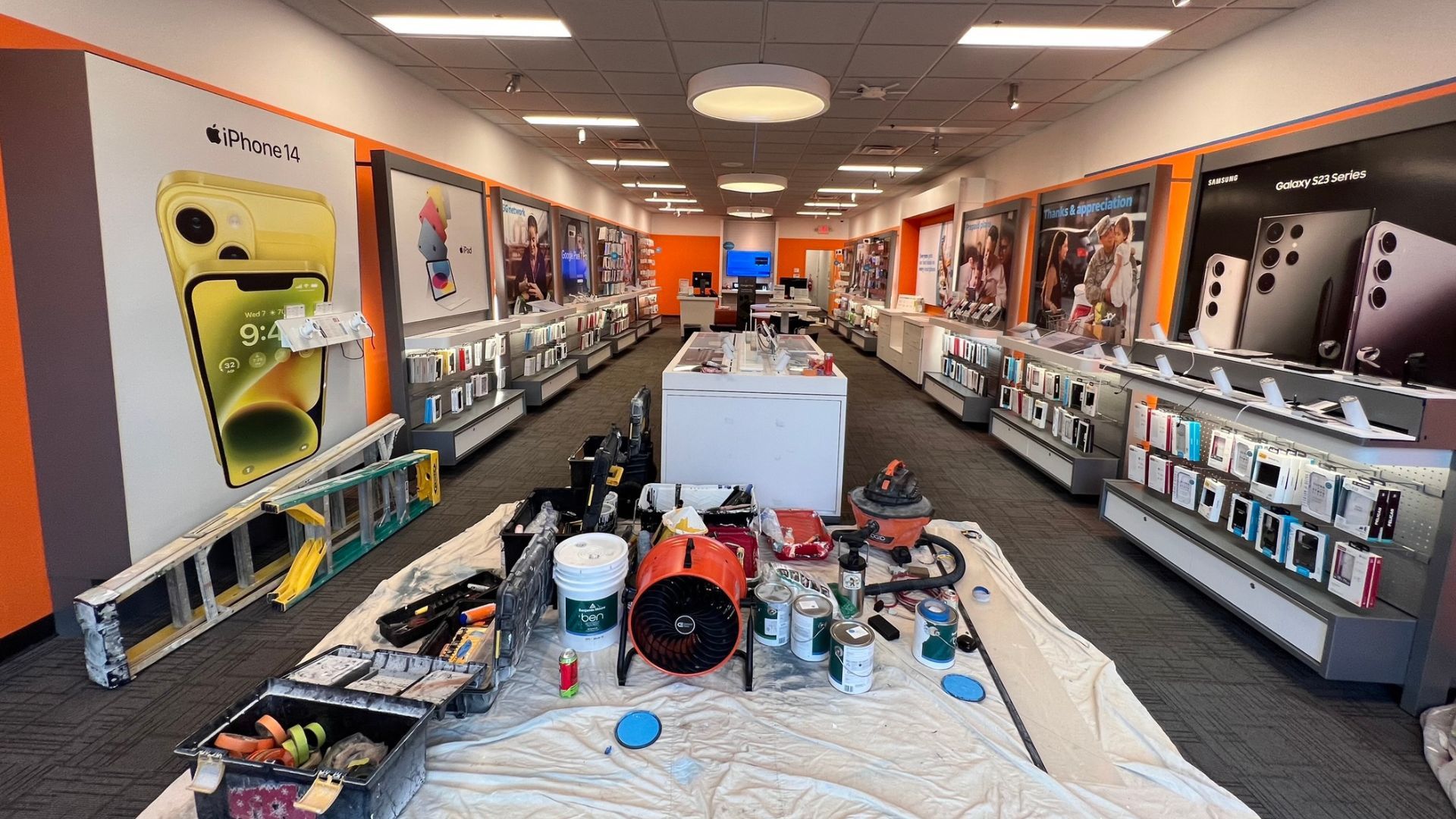 Office prep for commercial painting: ladders, paint cans, and drop cloths in retail store