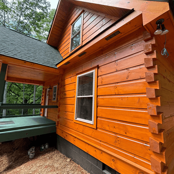 Professional Staining PB CTA Images Orange stained log cabin exterior with green porch