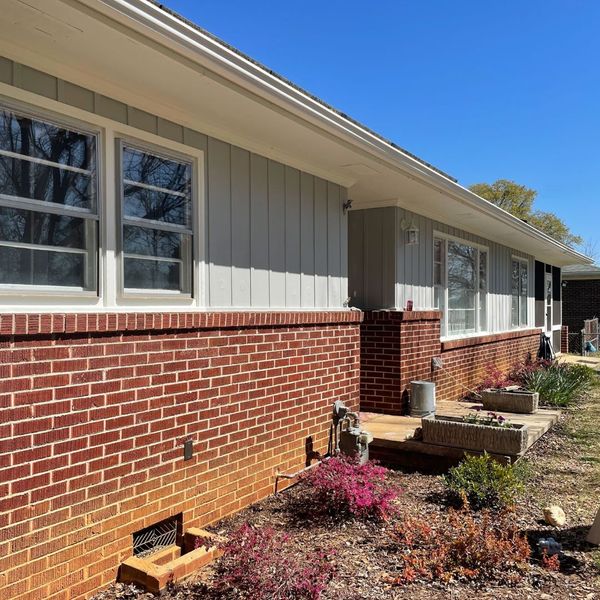 What to Do About 4 Exterior of a house with gray siding and red brick, showing potential cracking hardie boards.