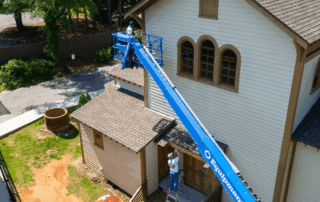 Aerial View Painters Working On Church Exterior Lift Workers in a boom lift paint a building, part of a construction portfolio.