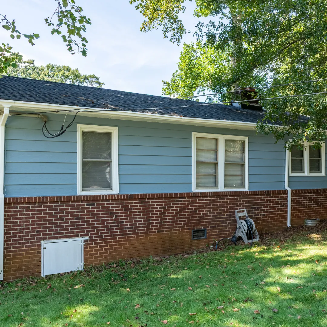 Exterior of a blue and brick house with a green lawn.