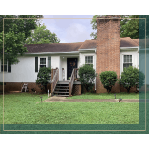 Exterior view of a white ranch-style house with a brick chimney and a well-maintained lawn.