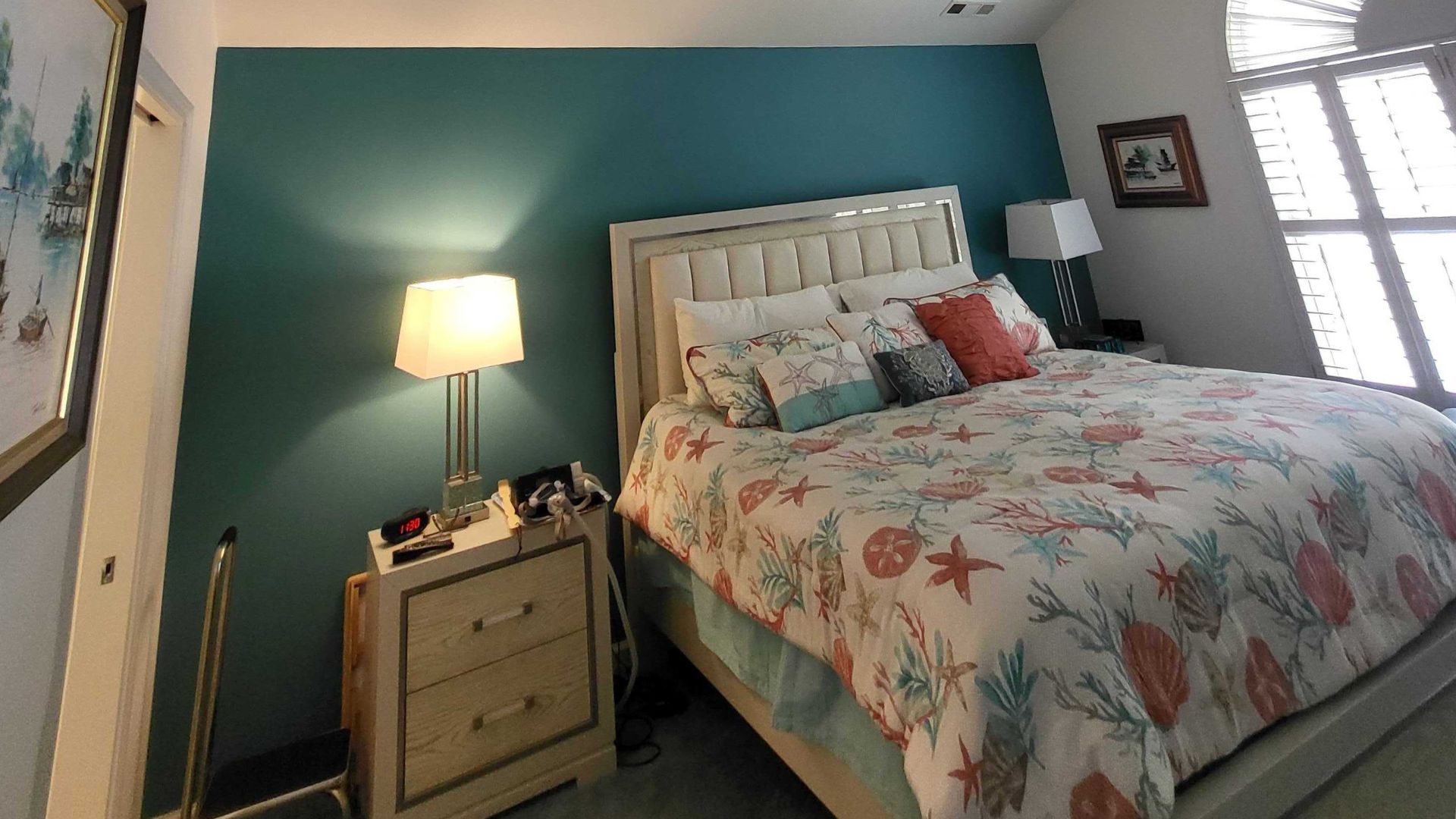 Teal bedroom accent wall behind a bed with coral and starfish bedding