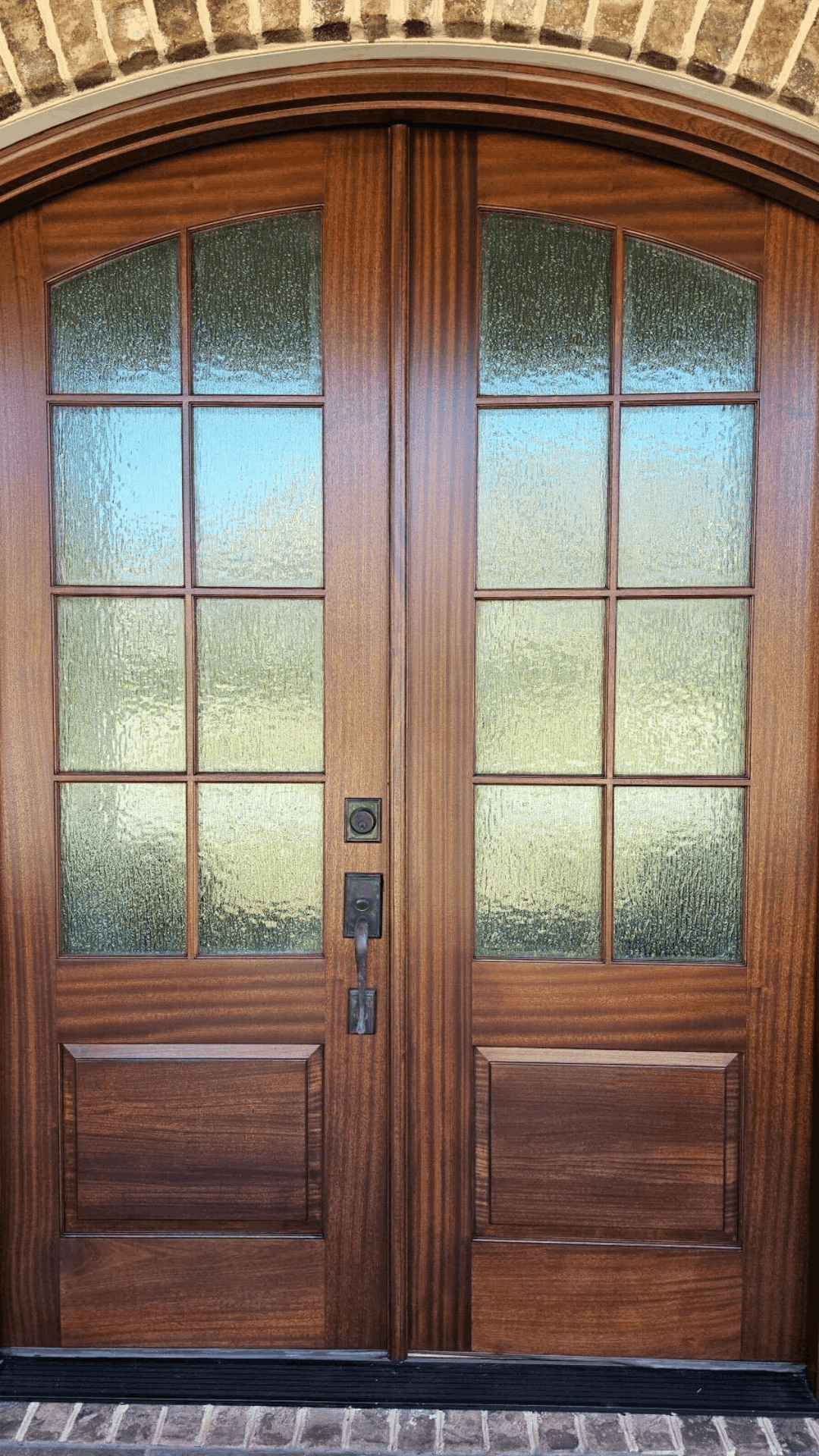Richly stained double wooden doors with glass panes, showcasing professional staining services.