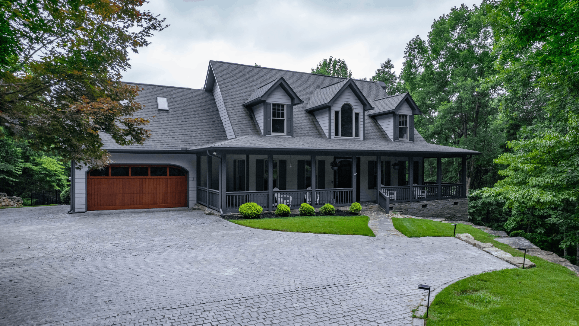 Gray home exterior with a covered porch and large garage door, ideal for painting.