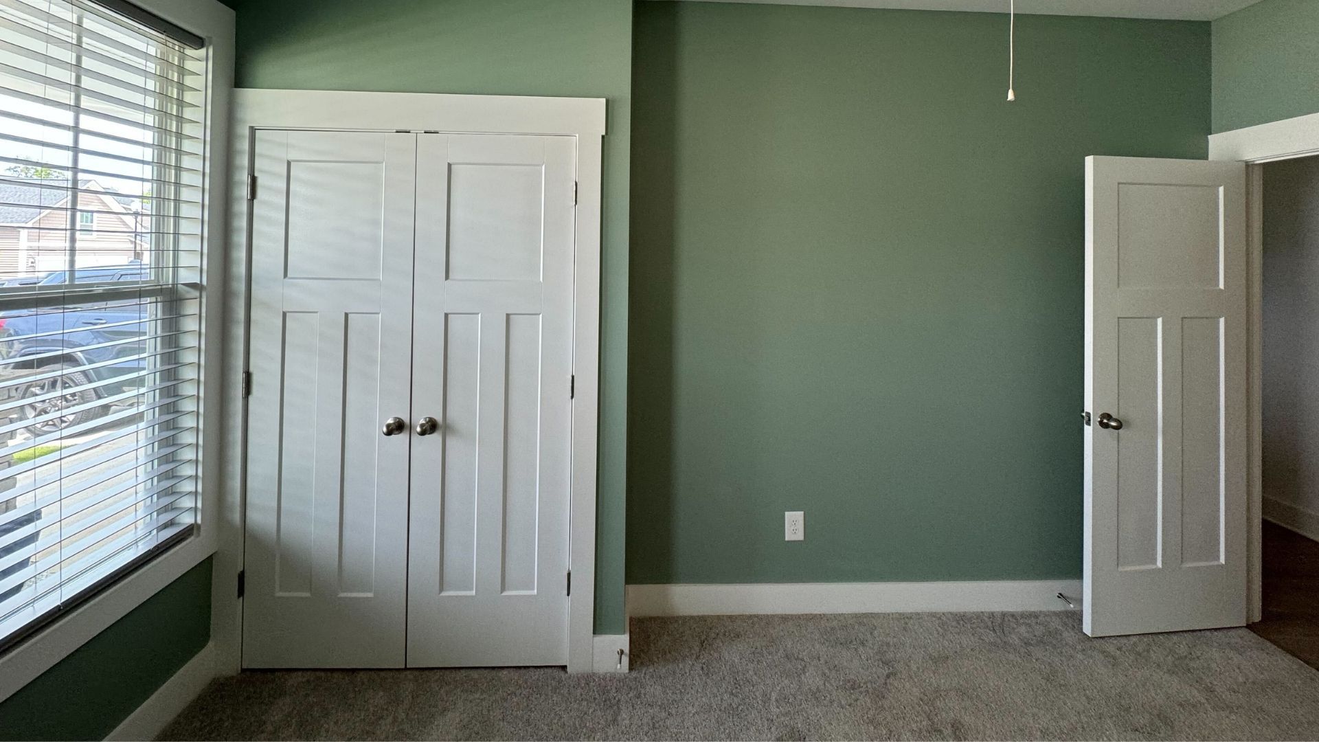 Green bedroom with white doors and windows, ready for new carpet.
