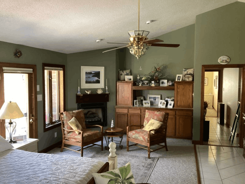 Green Bedroom Sitting Area Fireplace Ceiling Fan Cozy bedroom with fireplace, armchairs, and built-in cabinetry