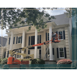 Exterior painting: Lift with worker painting large house with columns