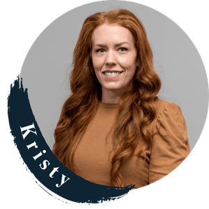 Kristy, a woman with long red hair, smiling in a circular frame.