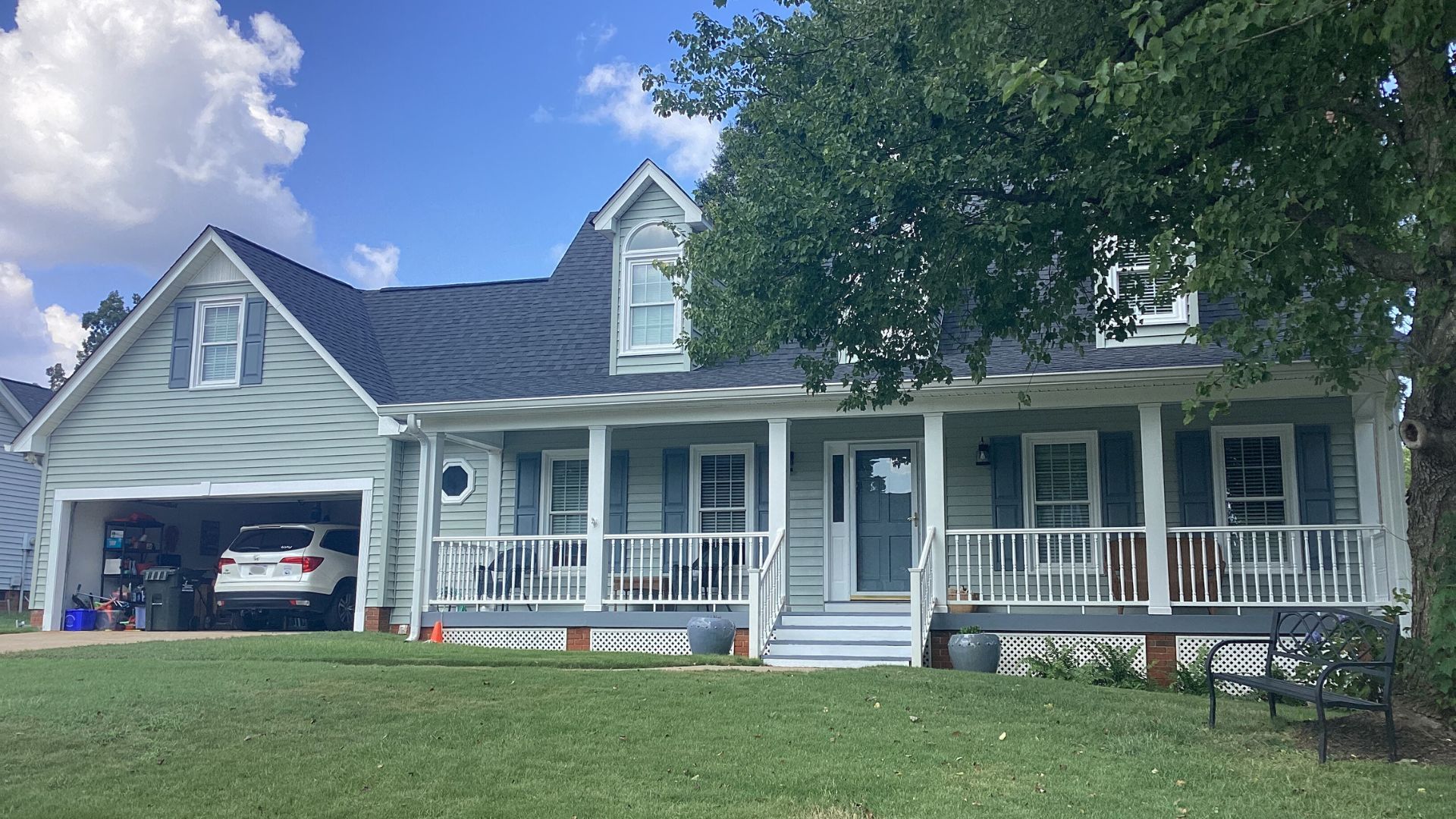 Sage green siding on a suburban home with white trim and blue shutters.