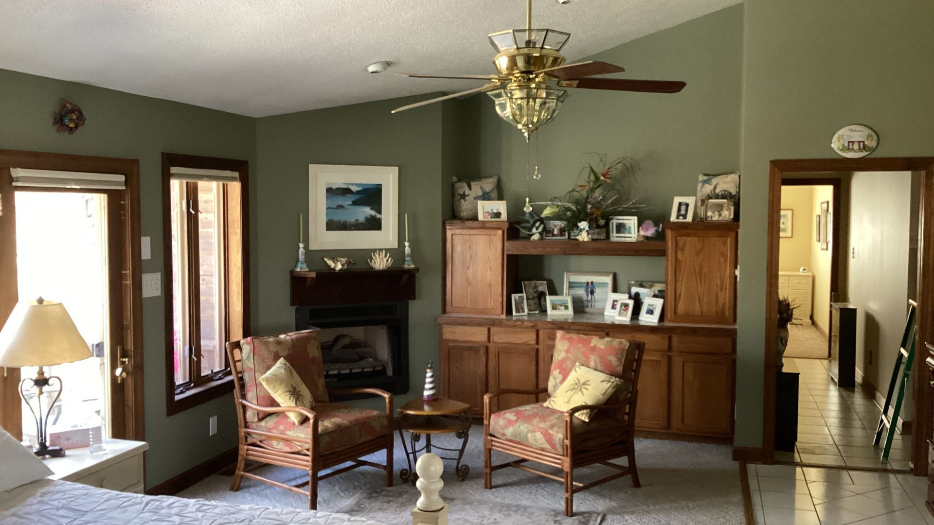 Green living room with fireplace, chairs, and built-in cabinets