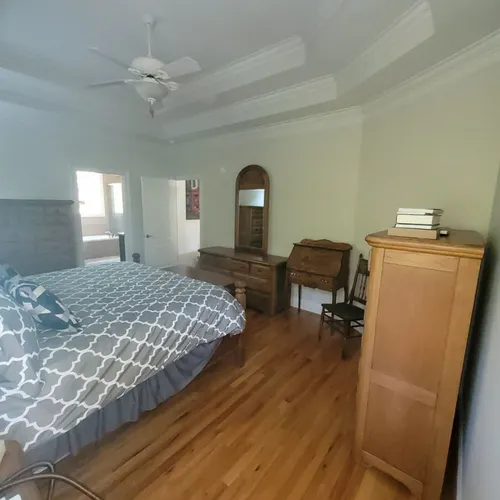 Master bedroom with king-size bed, wooden furniture, and tray ceiling