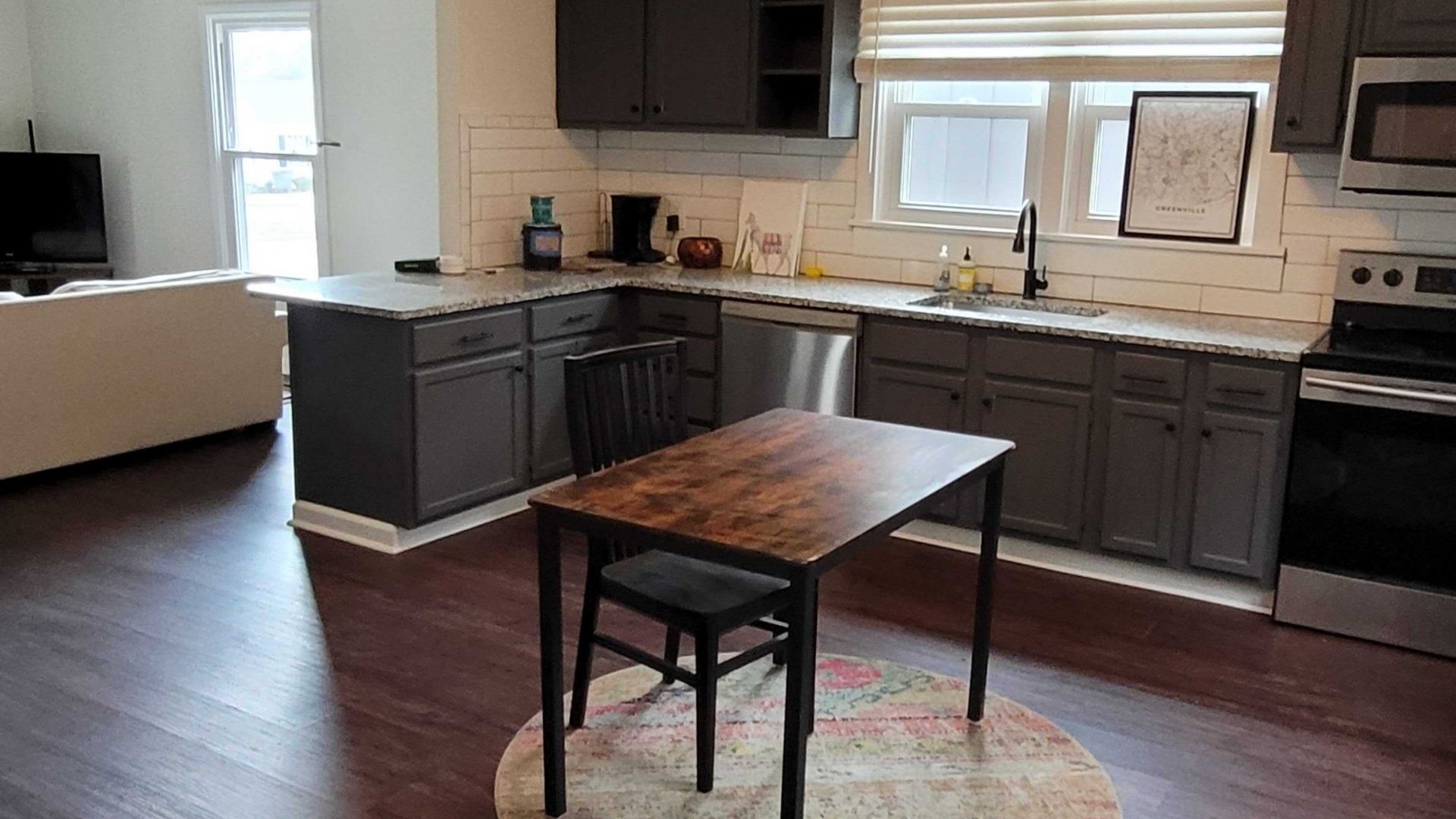 Modern kitchen with dark gray cabinets, granite countertops, and a small dining table.