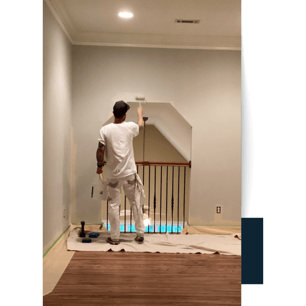 Painter Rolling Wall In Staircase Area Painter in Greenville County applying white paint to a wall with a roller.