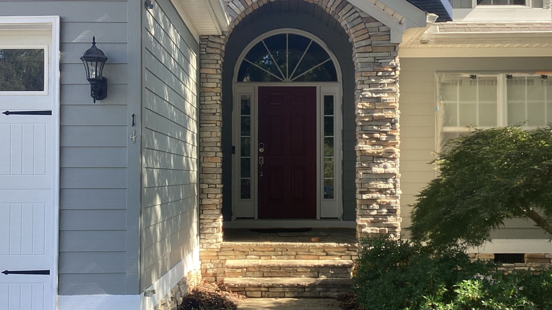 Red front door with arched stone entryway, showing exterior paint.