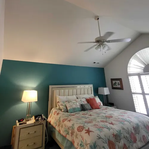 Master bedroom with teal accent wall, king-size bed, and ceiling fan.