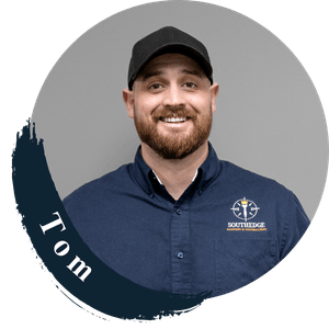 Tom, a smiling man wearing a navy blue shirt with a logo, featured in the About Us section.