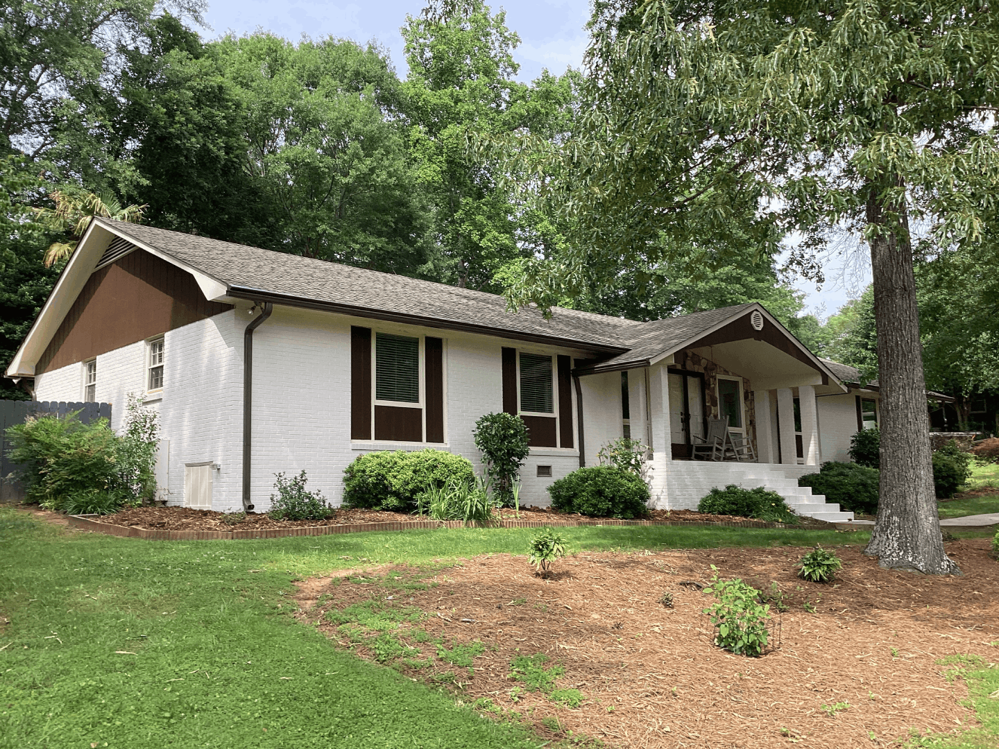 White brick ranch home with brown trim and a covered porch