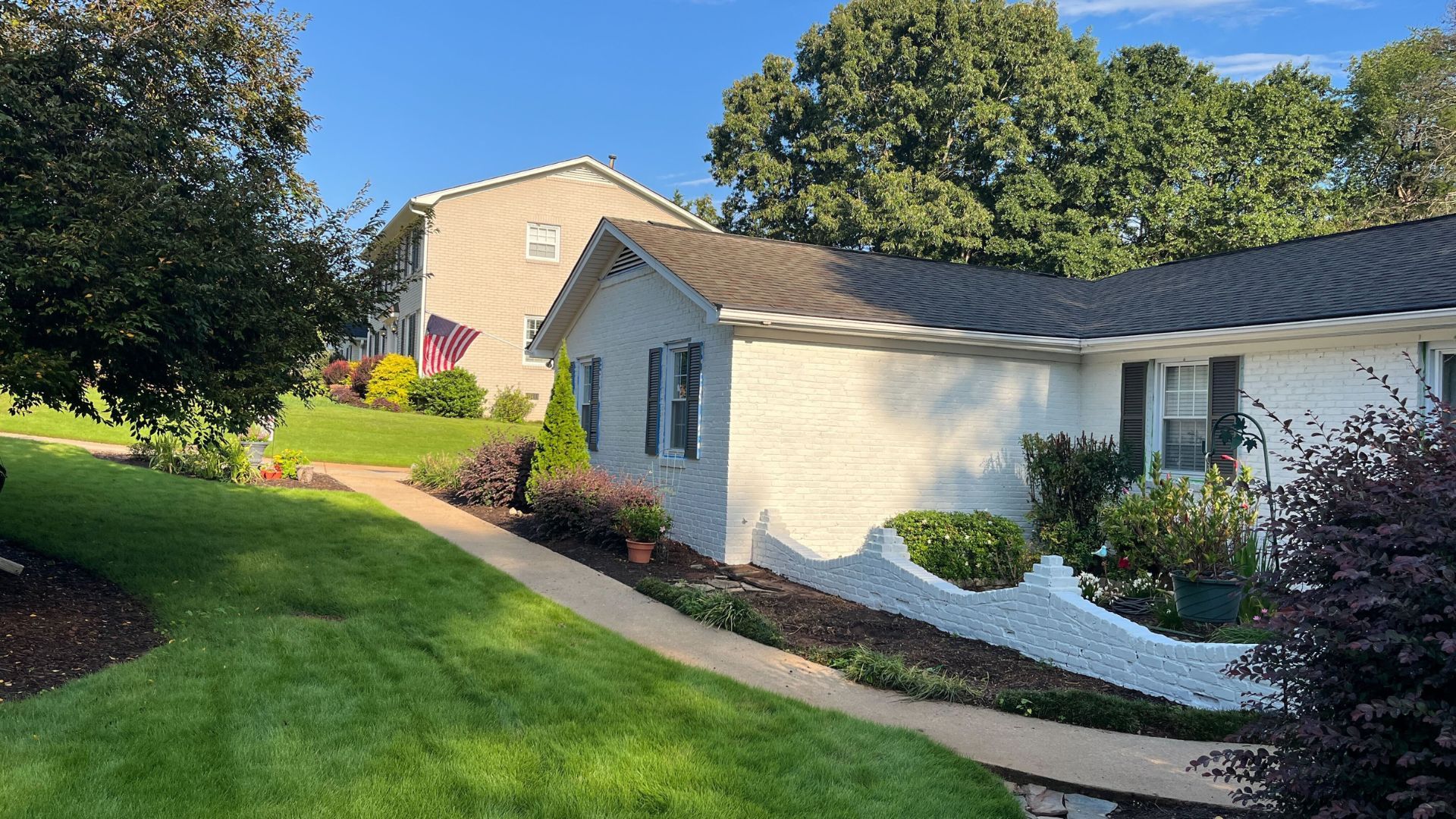 White painted brick house exterior with manicured lawn and trees